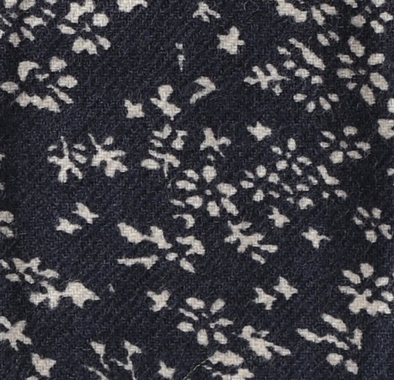 Detalle tejido corbata de lazo gris con flores blancas